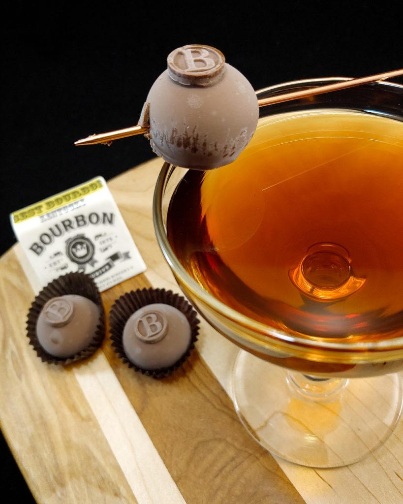 cocktail garnished with chocolate truffle on a wooden board