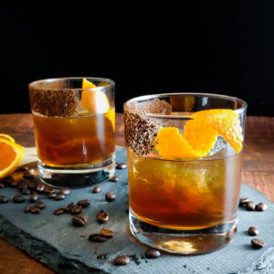 two cocktails with orange garnish