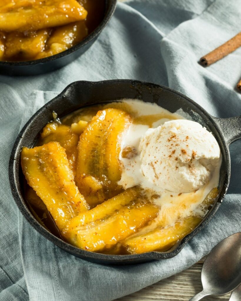 skillet of bananas foster topped with vanilla ice cream
