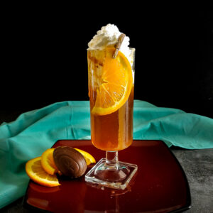 cocktail in a tall glass with whipped cream and orange