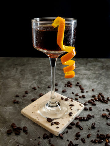 cocktail in glass with orange garnish