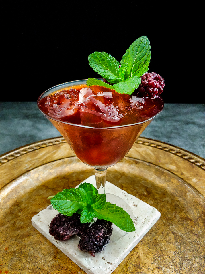 magenta cocktail in glass garnished with mint