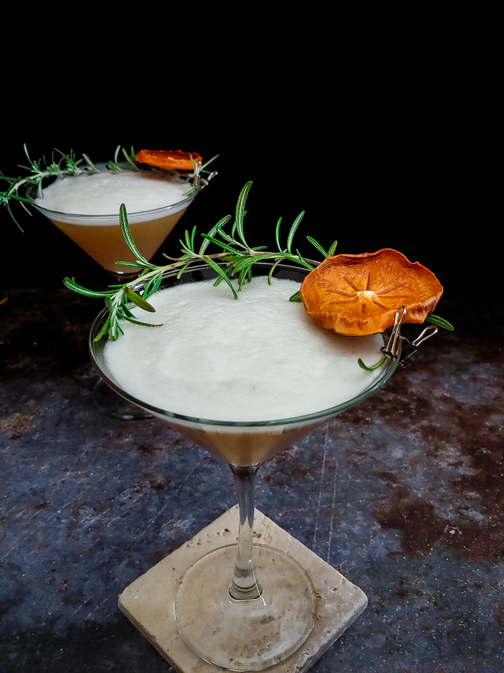 cocktail in martini glass with rosemary and dried persimmon