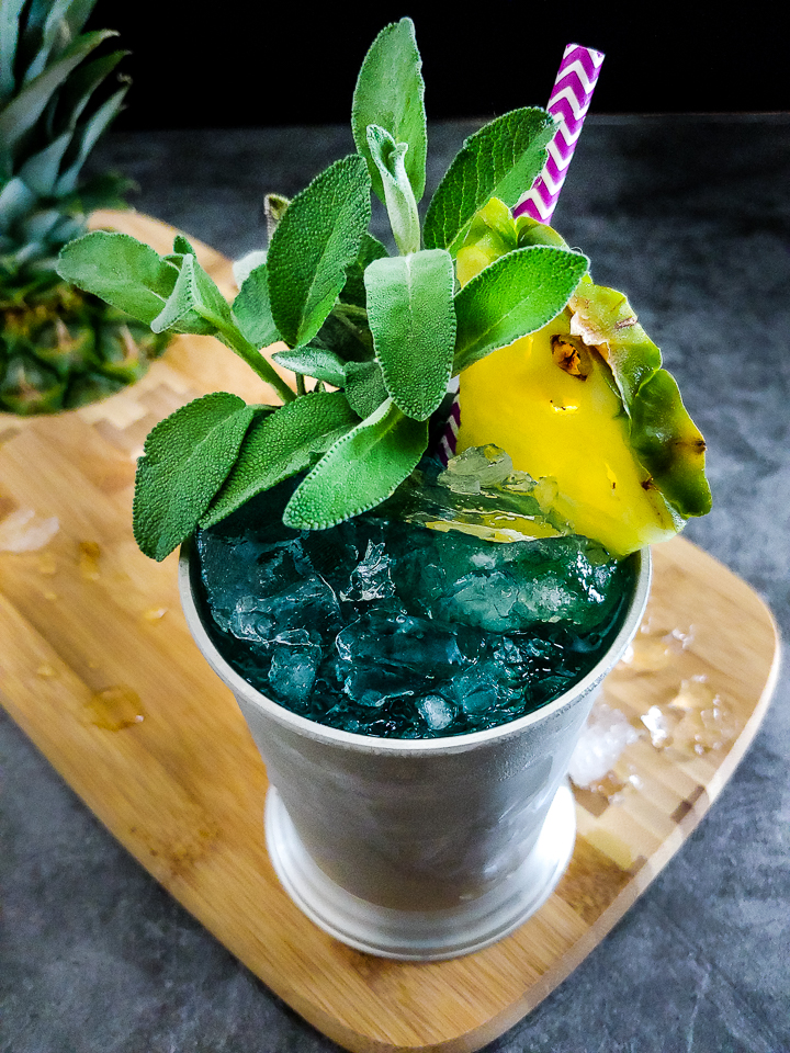 blue cocktail in metal julep cup with sage garnish