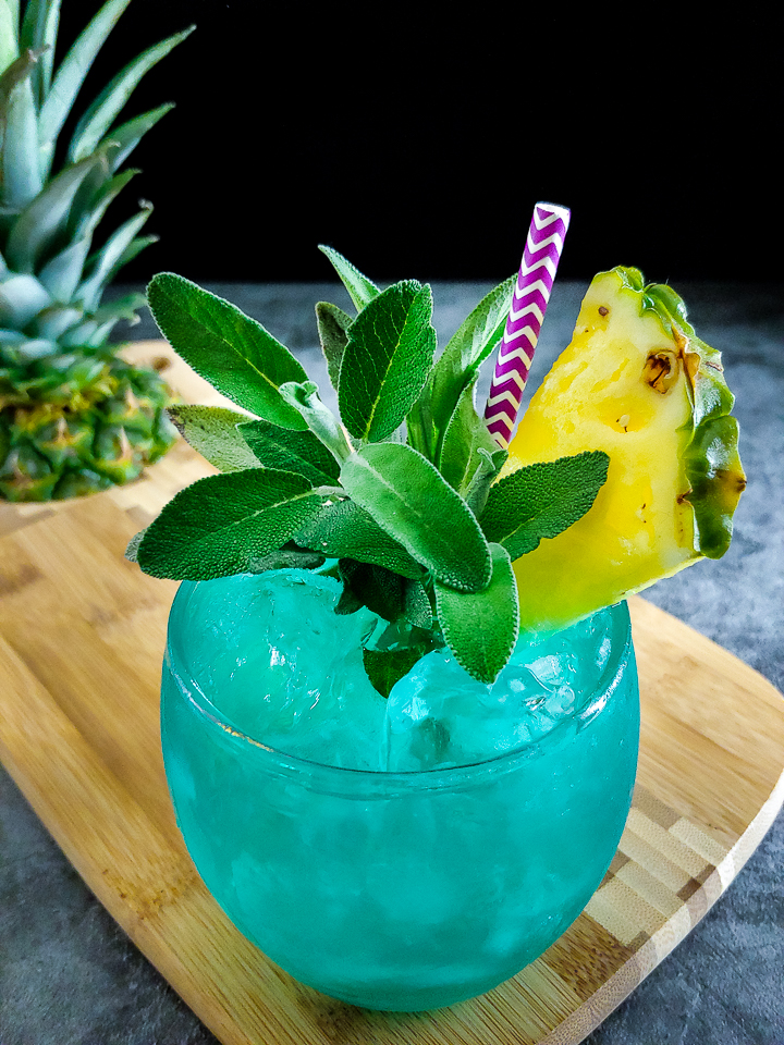 blue cocktail with pineapple sage garnish