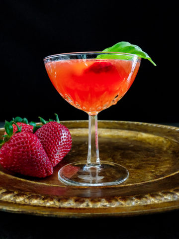 strawberry cocktail in coupe glass with strawberry and basil garnish