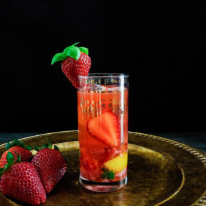 strawberry cocktail in highball glass with strawberry and basil garnish