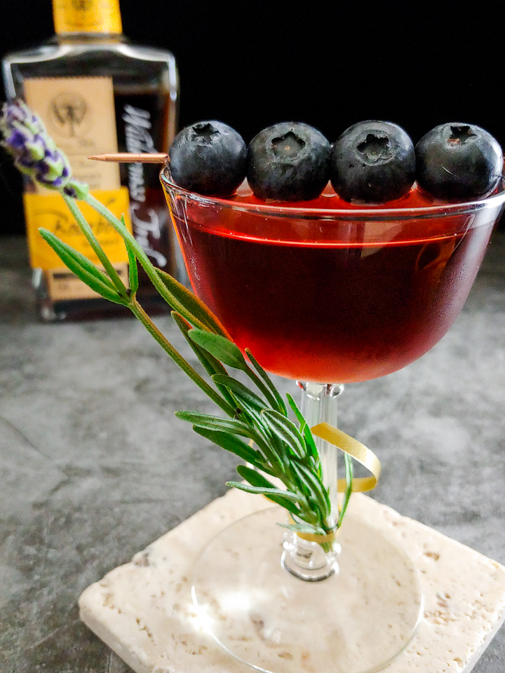 cocktail with lavender and blueberry garnish, Wilderness Trail bourbon in background