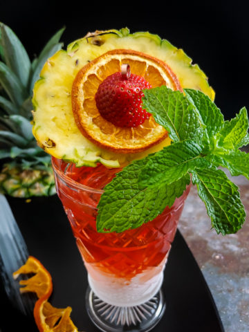 pink tiki cocktail with pineapple round and mint