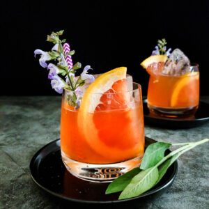 grapefruit mezcal cocktail with grapefuit and sage flower garnish
