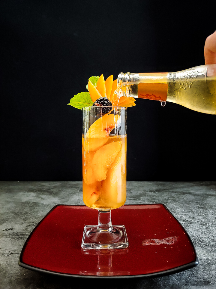 peach and whiskey highball with peach fan and basil garnish