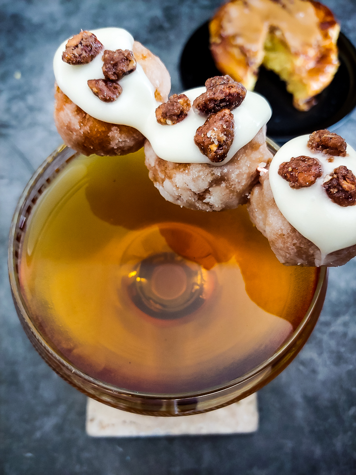 cocktail with donut holes garnish, glazed with icing and candied pecans