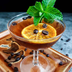 rum cocktail with mint and orange chip garnish