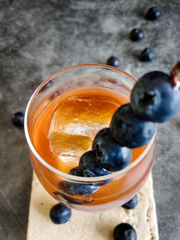old fashioned in rocks glass with blueberry skewer