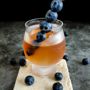 old fashioned in rocks glass with blueberry skewer