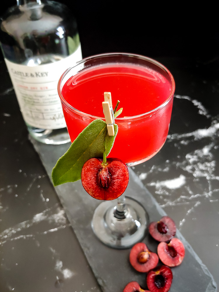 cherry gin smash in a coupe glass with sage and fresh cherry garnish