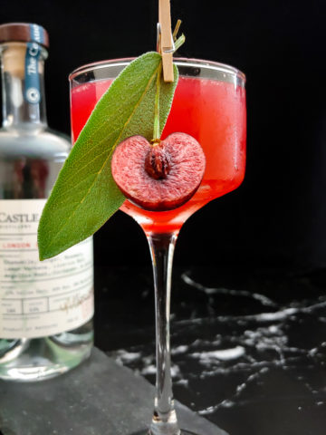 cherry gin smash in a coupe glass with sage and fresh cherry garnish