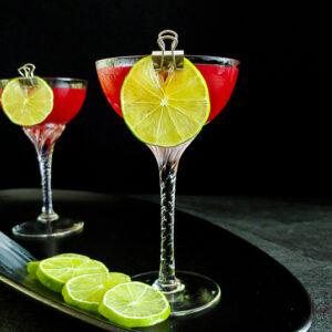 cherry gimlet cocktail with sage leaf and lime wheel garnish