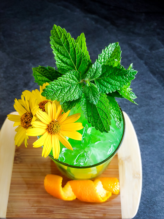 a green mule with mint, orange and flower garnish