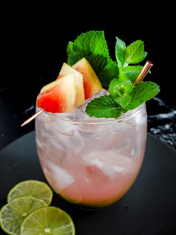 light pink tequila cocktal on rocks with watermelon and mint garnish