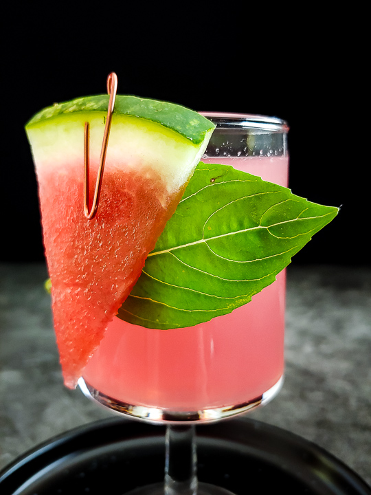 watermelon cocktail with watermelon and basil garnish