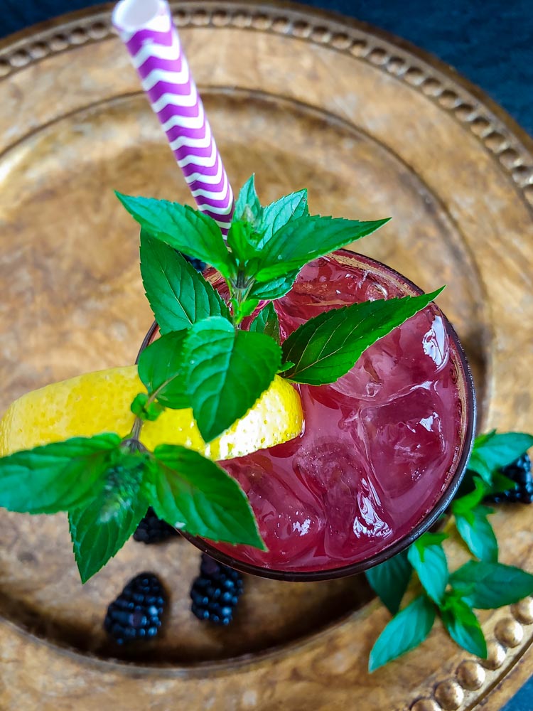 blackberry bourbon cocktail in highball glass with lemon and mint garnish