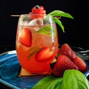 champagne bourbon cooler cocktail with strawberry and basil garnish