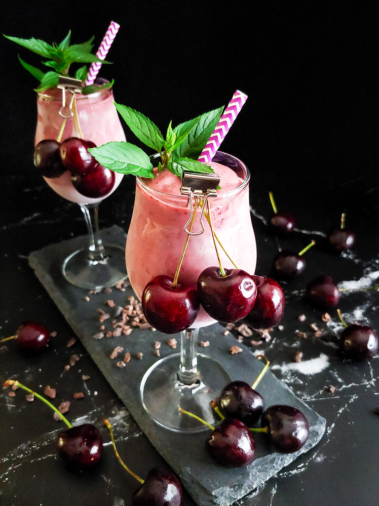 two cherry bourbon milkshakes in wine glasses with mint and cherry garnish