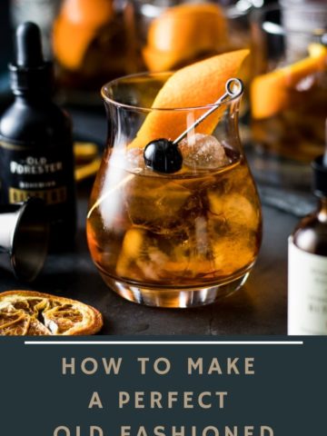 a perfect old fashioned in a rocks glass over ice with bitters and other old fashioned surrounding it. Garnished with orange peel and cherry