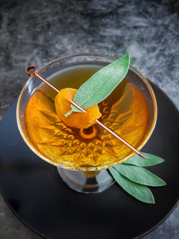 Uncle Nearest Apricot Manhattan cocktail in a coupe glass with apricot with a sage leaf