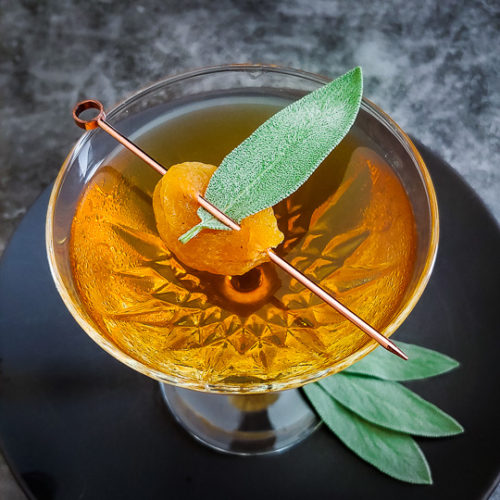 Uncle Nearest Apricot Manhattan cocktail in a coupe glass with apricot with a sage leaf