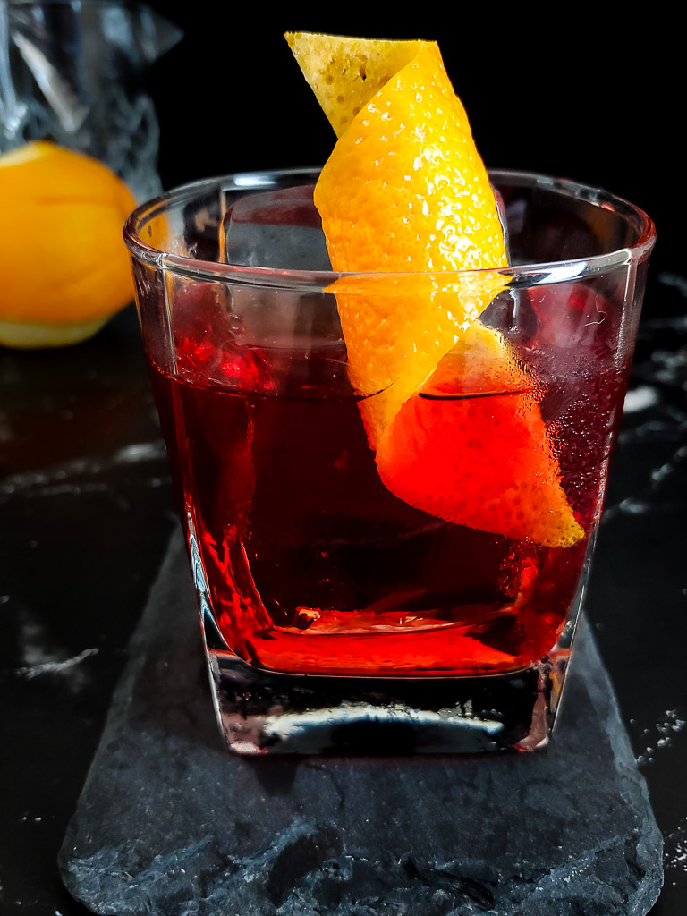 Negroni with bourbon on the rocks in a glass with citrus twist garnish.