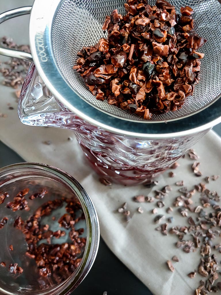 cacao nib campari infusion with nibs strained in metal seive