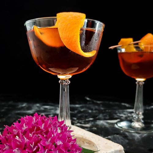 classic manhattan cocktail in a coupe with an orange garnish
