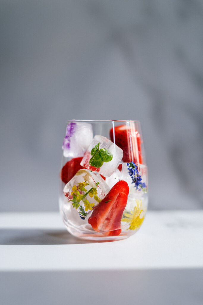 cup with ice cubes with fruit and herbs in them