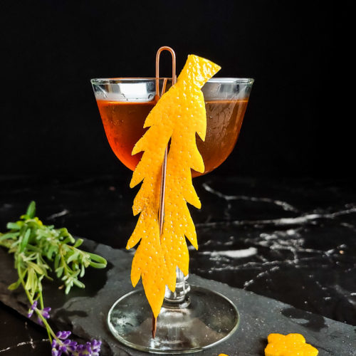 barrel proof manhattan cocktail in a coupe with an orange peel garnish