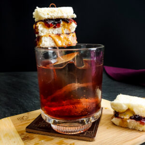 Peanut butter and jelly old fashioned with tiny pbj sandwich garnish