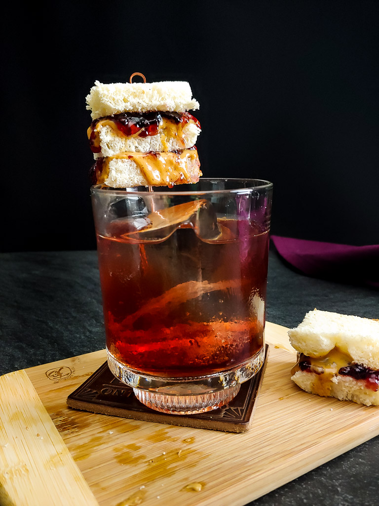 Peanut butter and jelly old fashioned with tiny pbj sandwich garnish