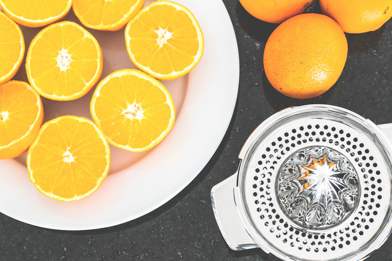 Oranges on a plate with a juicer for simple syrup