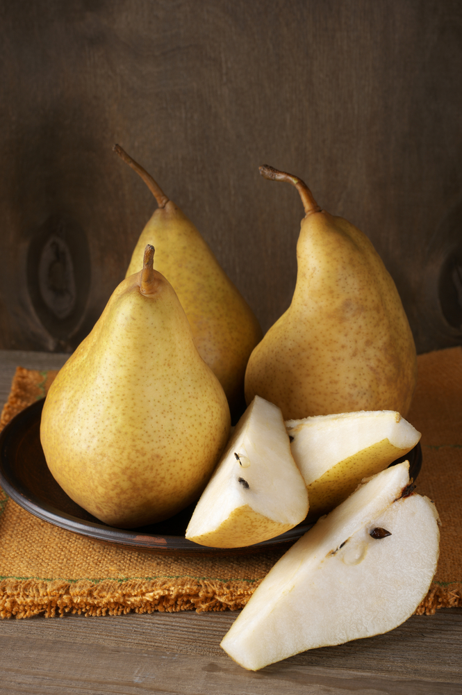 Pears on a plate. One sliced into quarters.