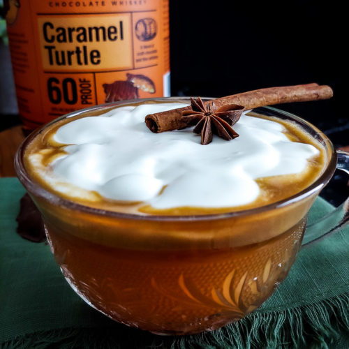 Hot Buttered Rum Cider with cinnamon stick and anise on a bed of whipped cream