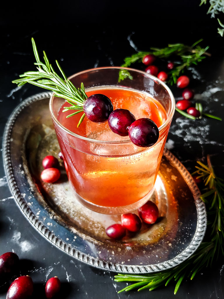 cranberry old fashioned with cranberry and rosemary sprig garnish
