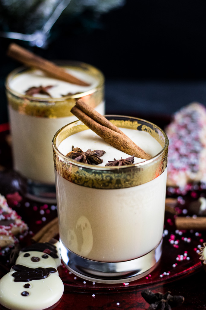 Bourbon spiked eggnog in gold rimmed glassware, garnished with cinnamon sticks and star anise.