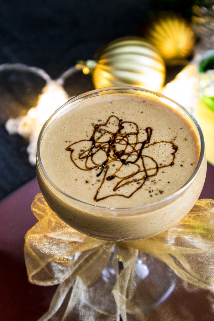 Gingerbread Martini in a coupe with a drizzle of molasses and holiday ornaments