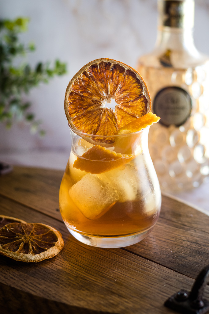 Earl Grey Cocktail with orange wheel and orange twist in ice-filled rocks glass
