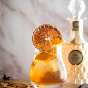 Earl Grey Cocktail with orange wheel and orange twist in ice-filled rocks glass