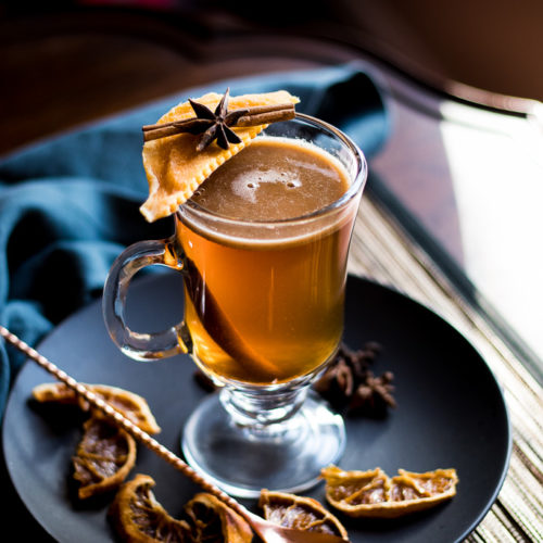 Indian Hot Buttered Rum - Kamala's Birthright - in a clear mug garnished with mango, cinnamon stick and star anise