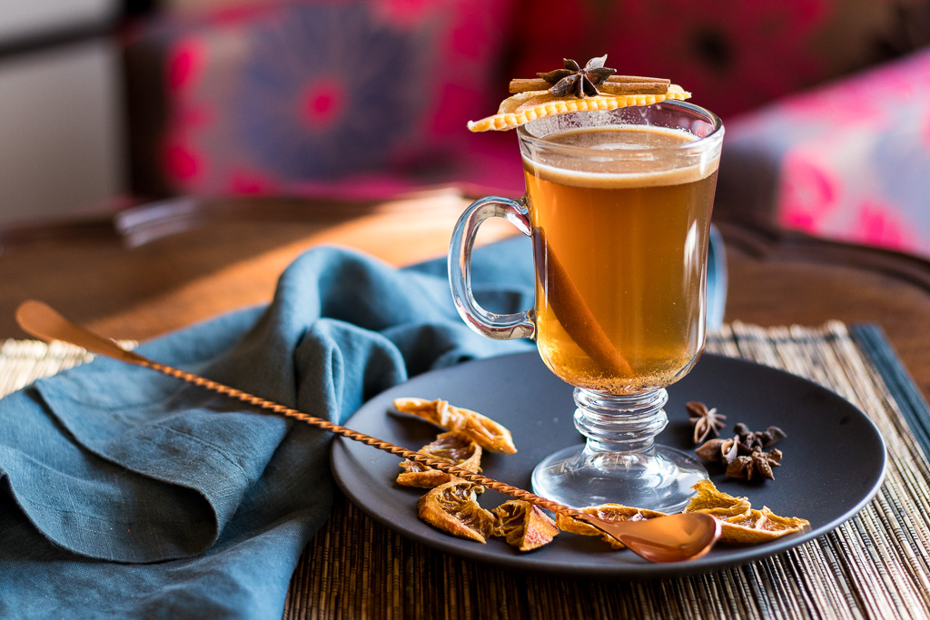 Indian Hot Buttered Rum - Kamala's Birthright - in a clear mug garnished with mango, cinnamon stick and star anise
