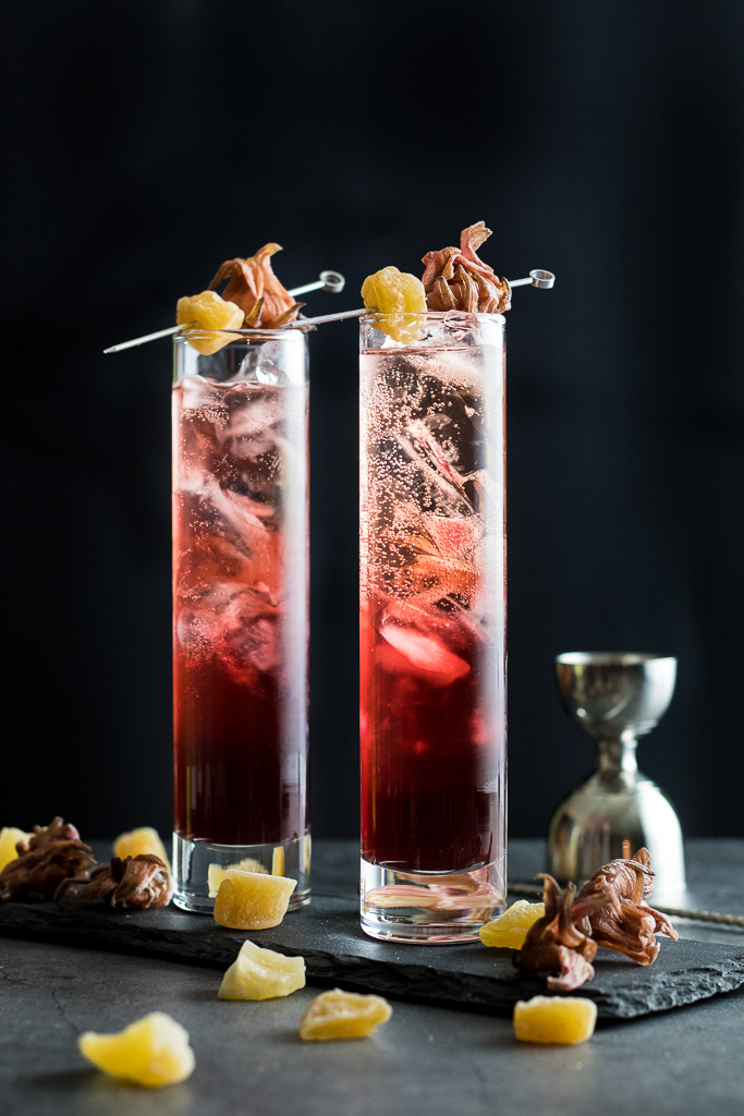 Hibiscus Highball in two glasses with hibiscus and candied ginger garnish