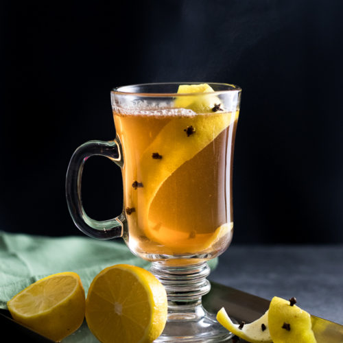 Easy Hot Toddy in a glass much with a lemon zest impaled with whole clove